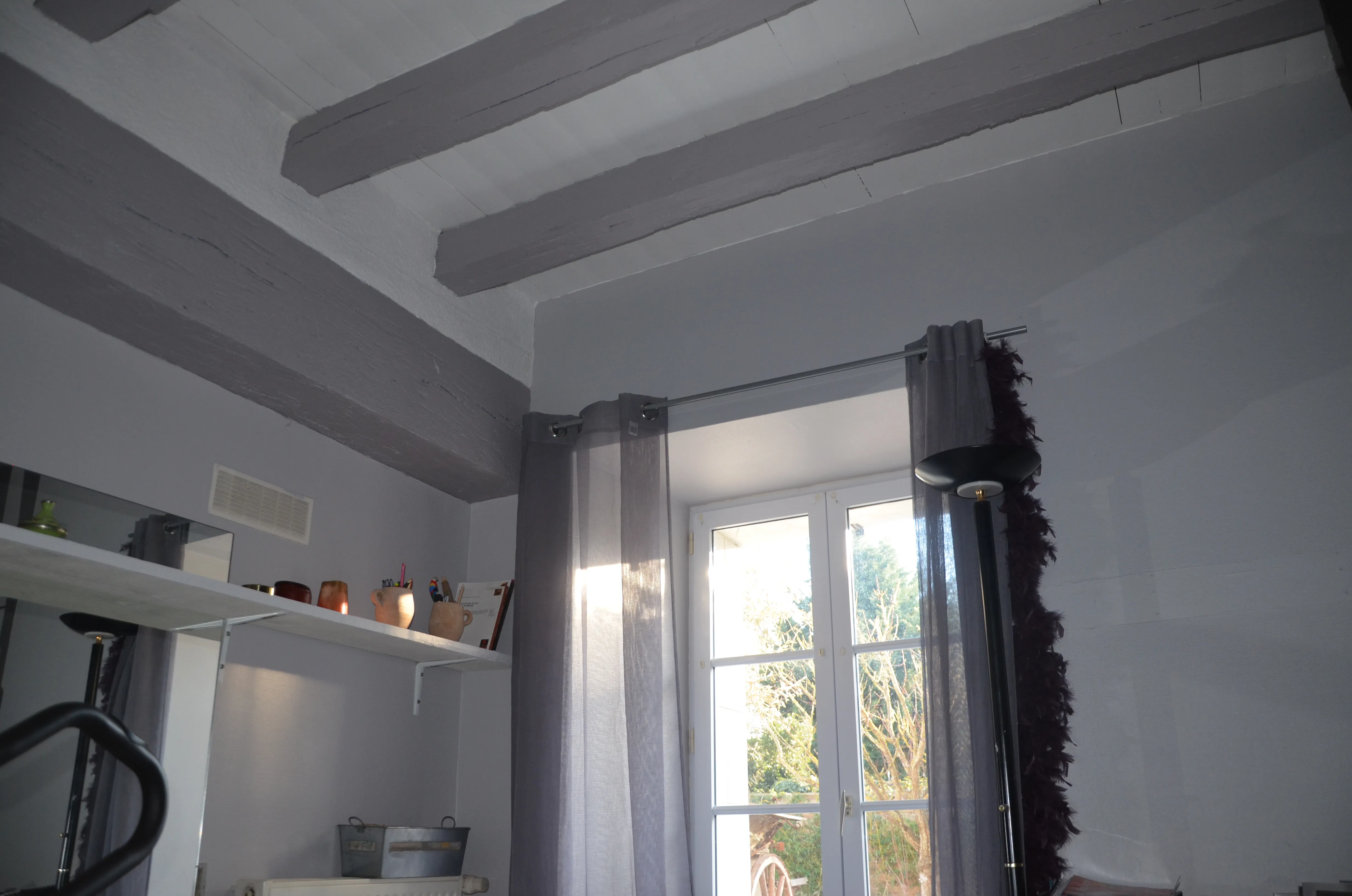 Pièce avec boiseries et poutres peintes, murs clairs contrastés