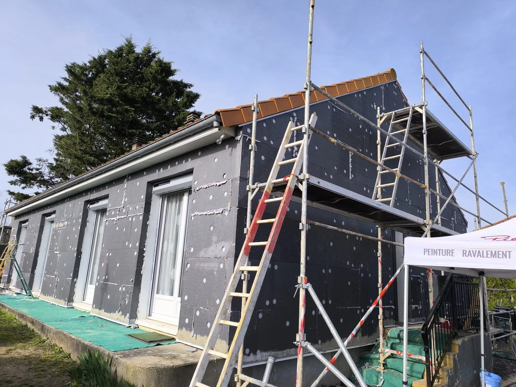 Chantier d'isolation thermique extérieure en cours, échafaudage et panneaux d'isolant visibles