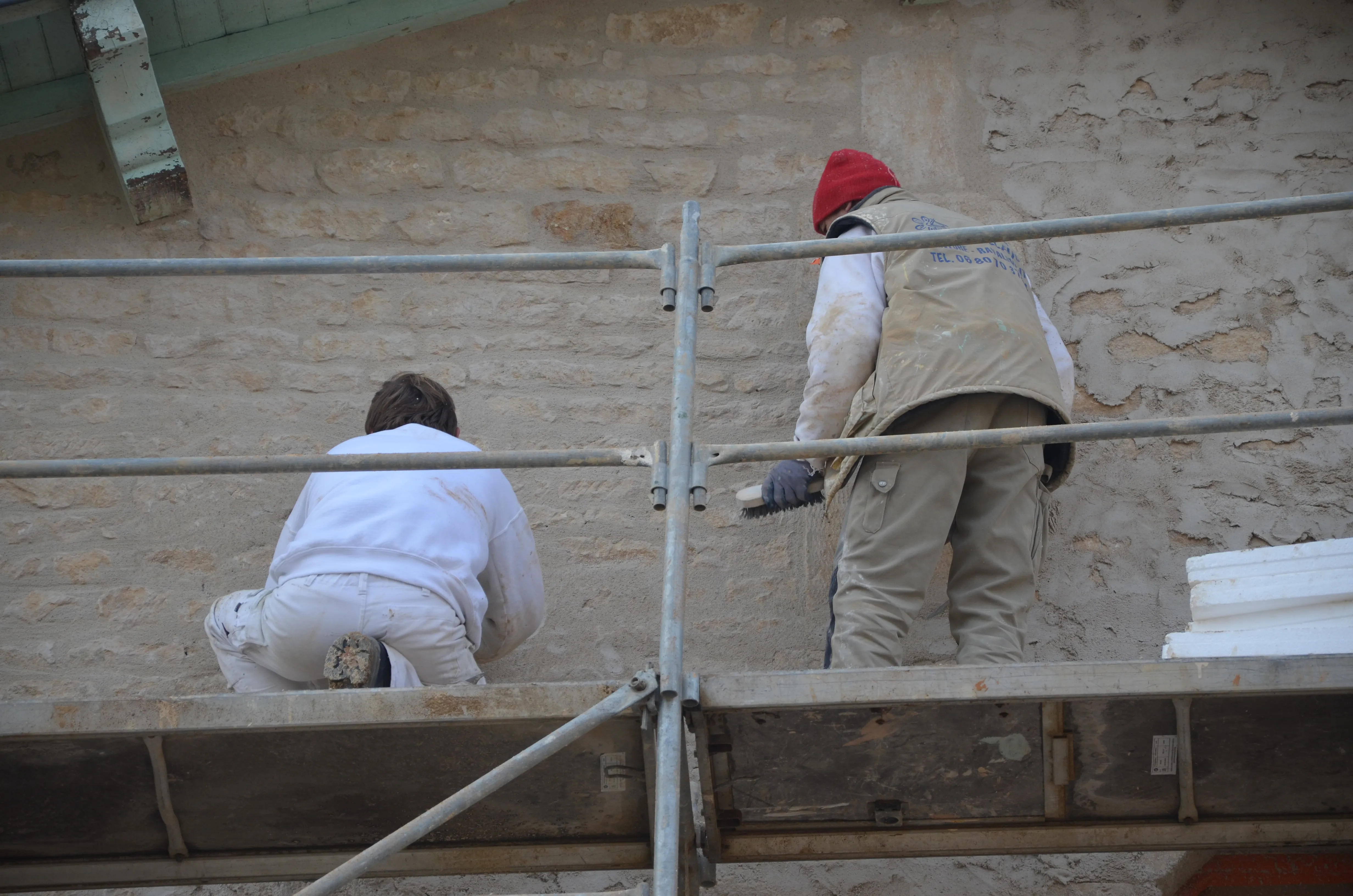 Artisan façadier de la SARL Pierre Millaud brossant un mur en pierres apparentes